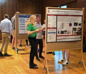 People have conversations about research with poster display while eating food.