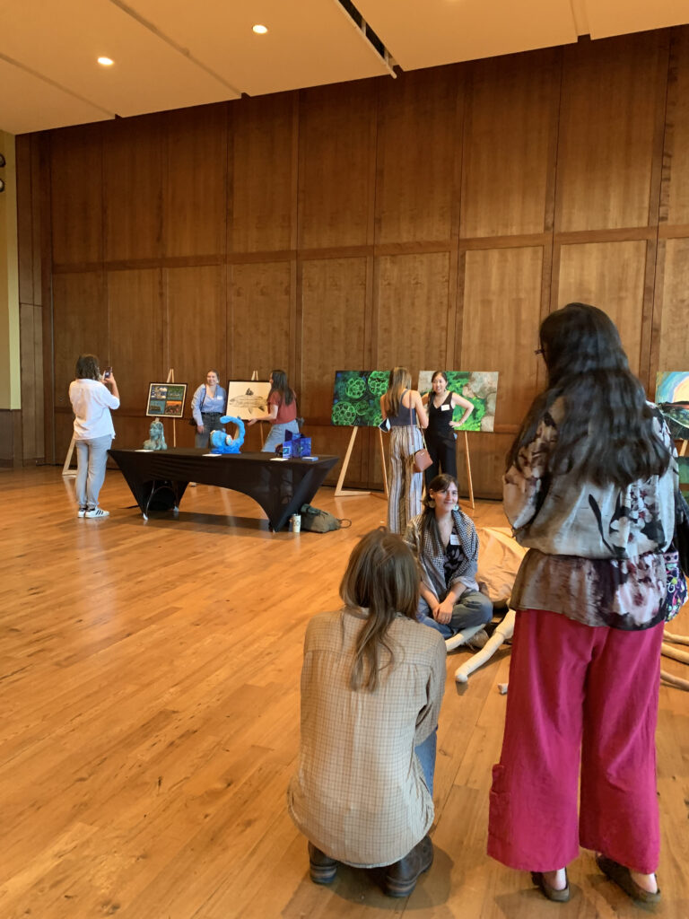 Family and friends take pictures of their artist with their artwork.