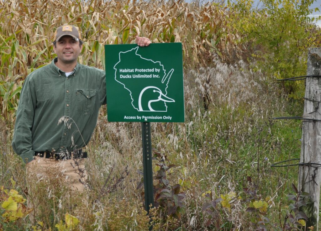 image of a man next to a ducks Unlimited sign