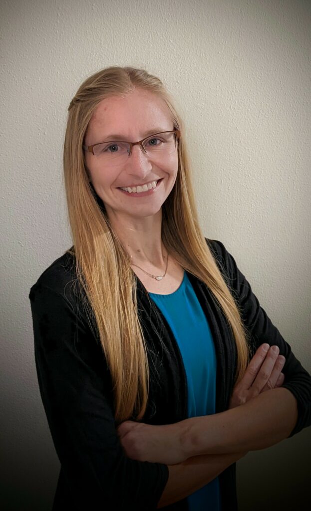 a blonde woman poses with her arms crossed