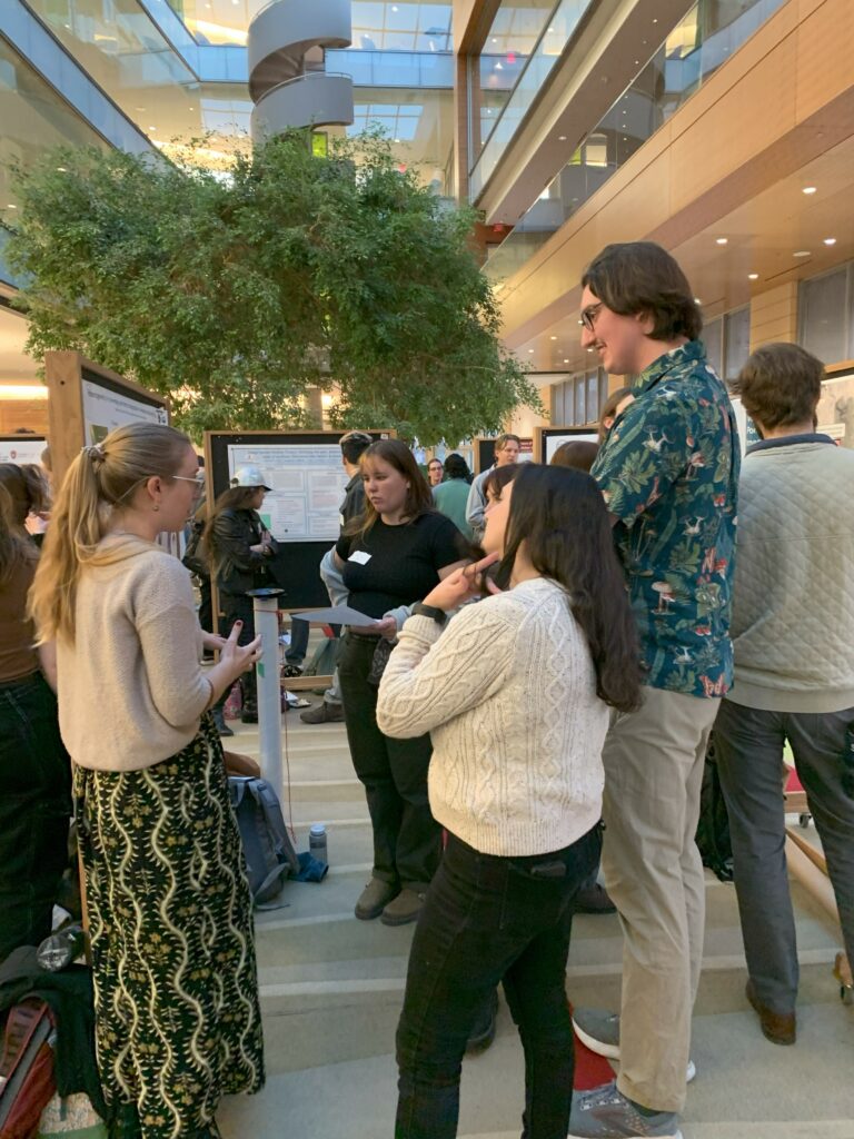 A group of people discuss water research at an art and science poster session.