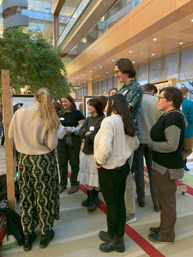 A group of people discuss water research at an art and science poster session.