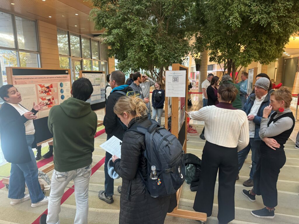 Attendees network and chat about water research at an art and science poster session.