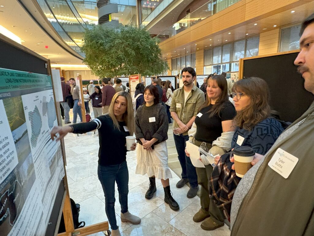 A group of people discuss water research at an art and science poster session.