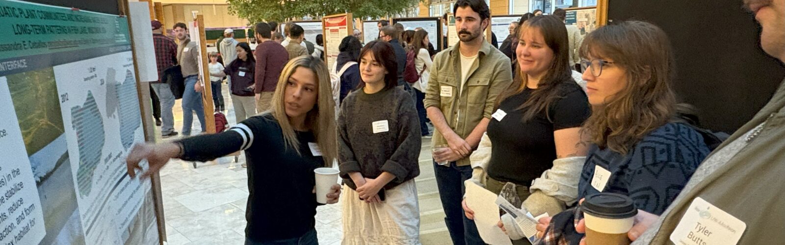 A group of people discuss water research at an art and science poster session.