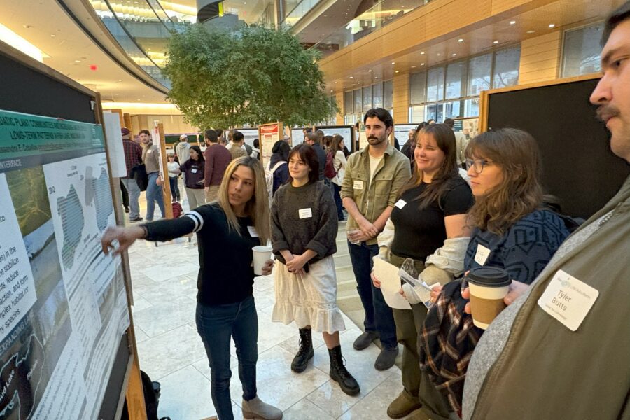 A group of people discuss water research at an art and science poster session.