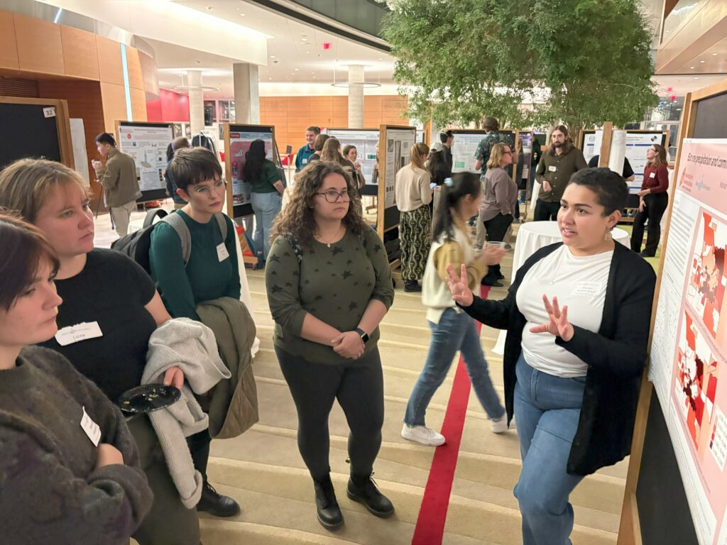 A group of people discuss water research at an art and science poster session.