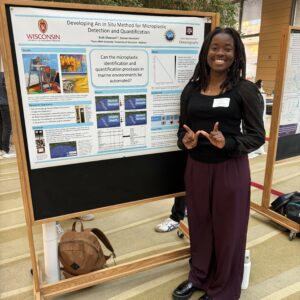 Researcher stands in front of a poster on microplastics detection.