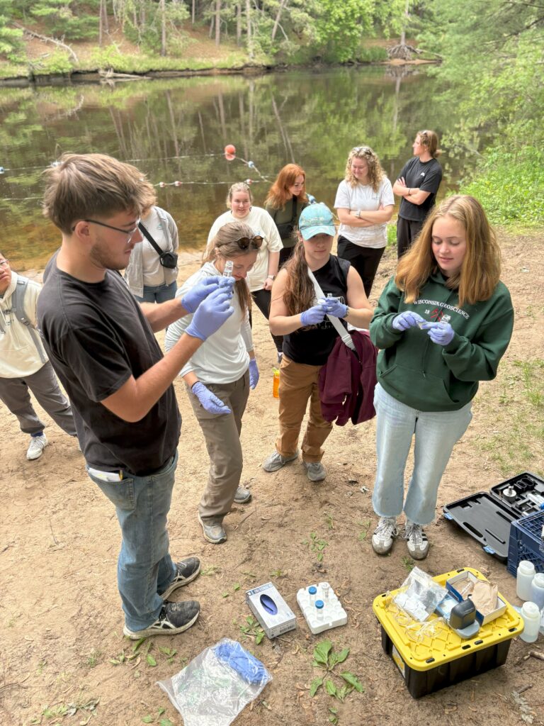 Students test phosphorus samples at the edge of a river