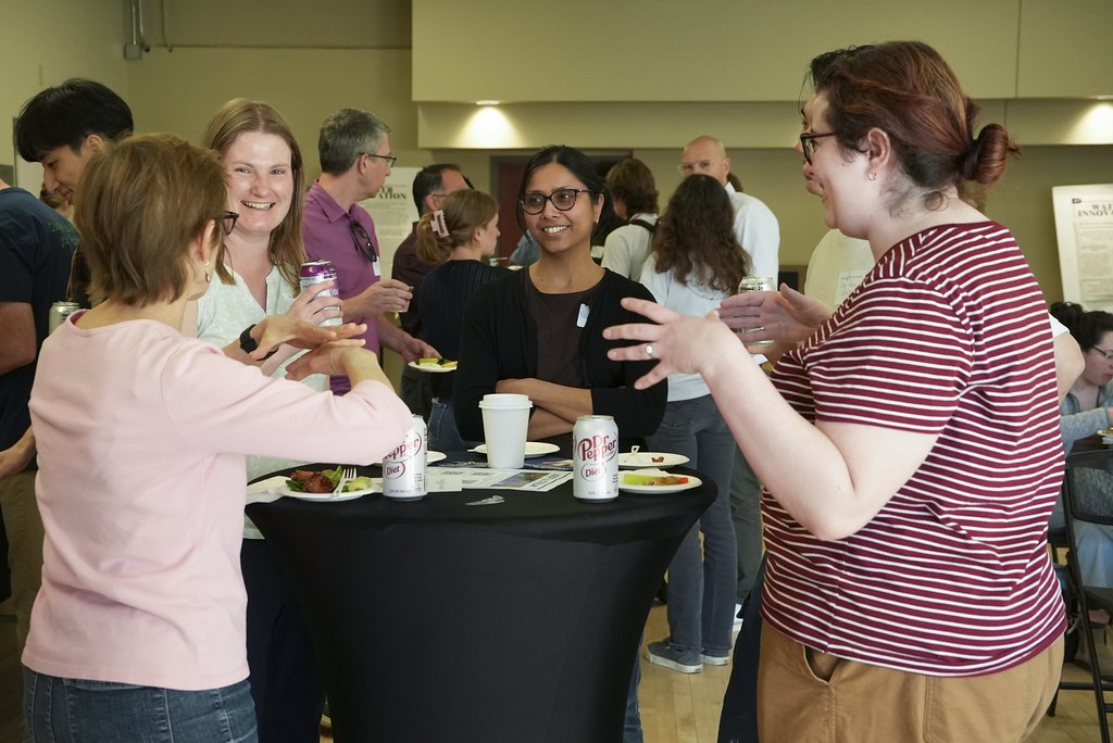 Four women talk standing around a table