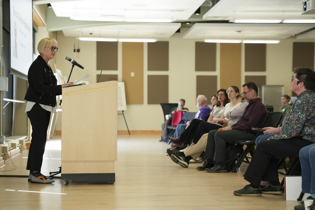 woman gives opening remarks behind podium