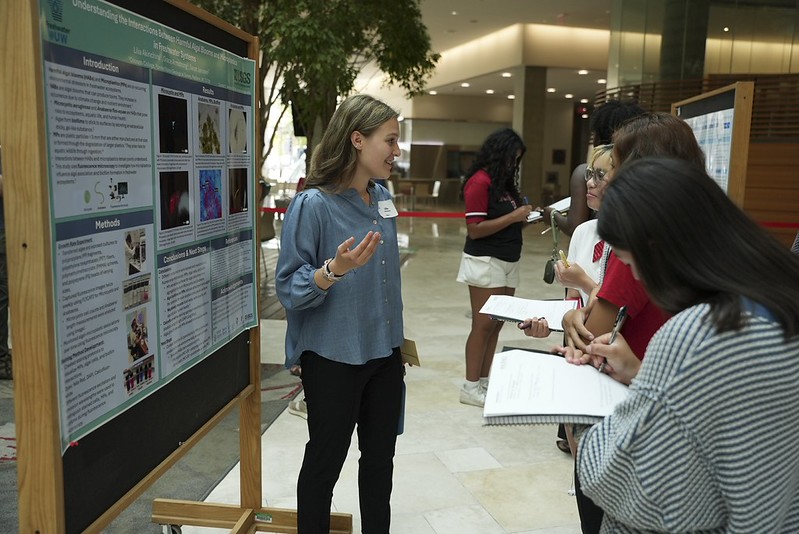 Student presents her poster to high schoolers