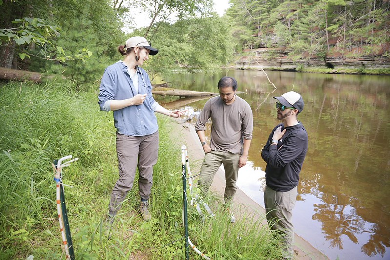People observing a groundwater well near a stream