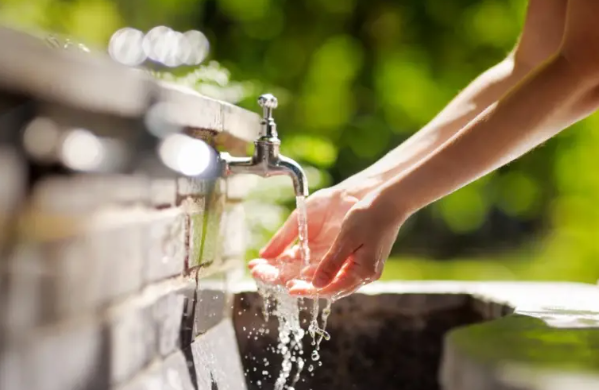 Clean water falls from a spigot onto human hands.